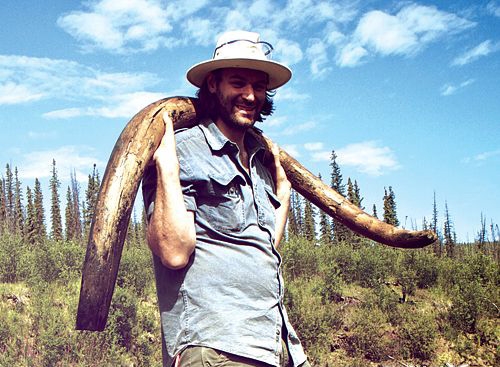 Le paléontologue Tyler Kuhn portant une défense de mammouth trouvée dans un gisement placérien à Dawson, au Yukon.